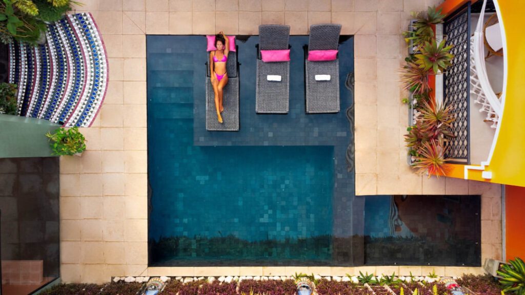 Woman sunbathing by the pool with an upside down view at Exotica Boutique Hotel