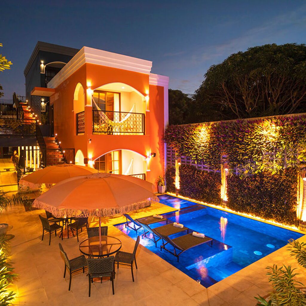 在Exotica精品酒店，有棕榈树和夜间照明的茂盛的游泳池